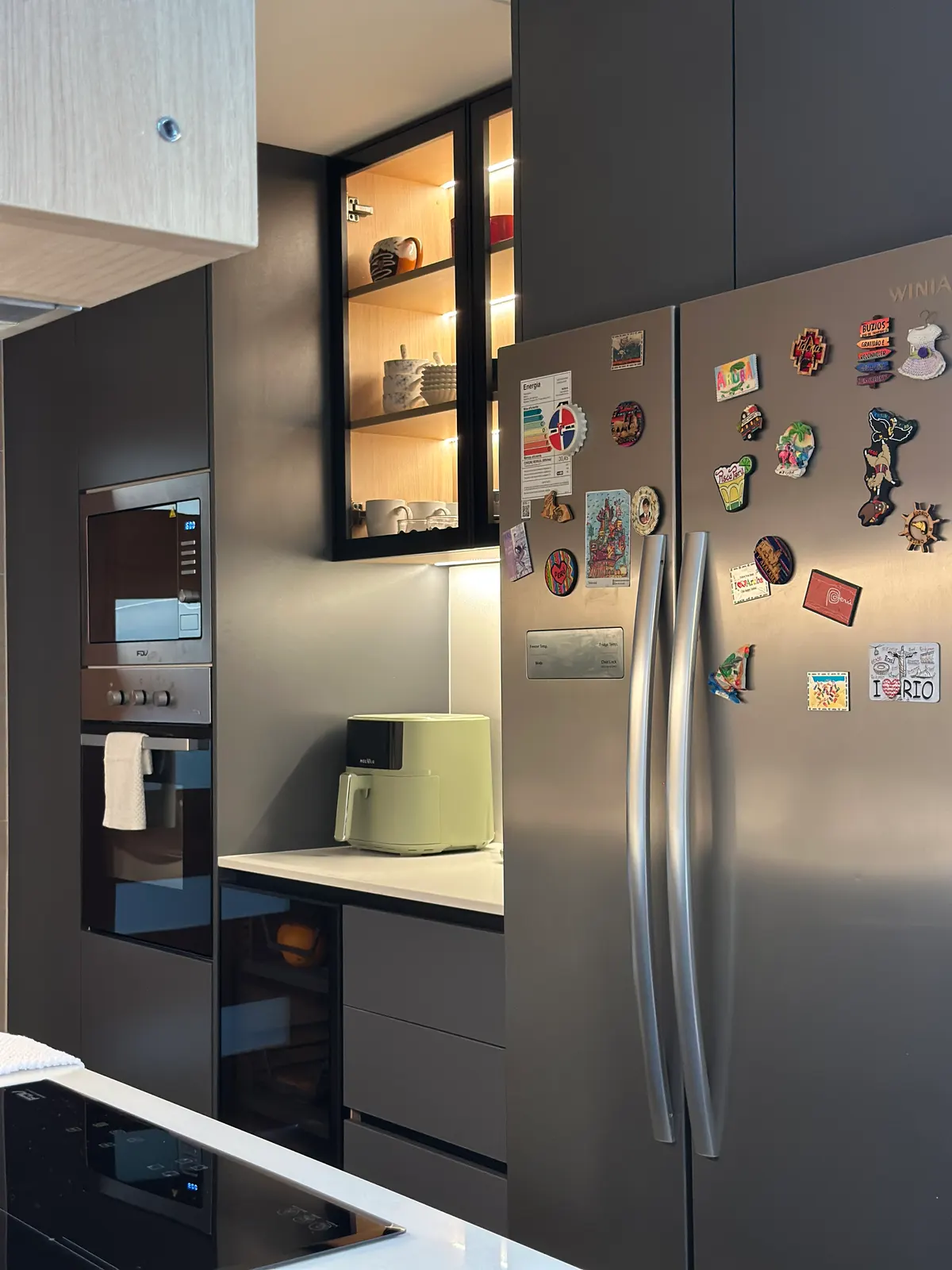 Refrigerador empotrado en la torre de grafito, junto a la vitrina de tazas