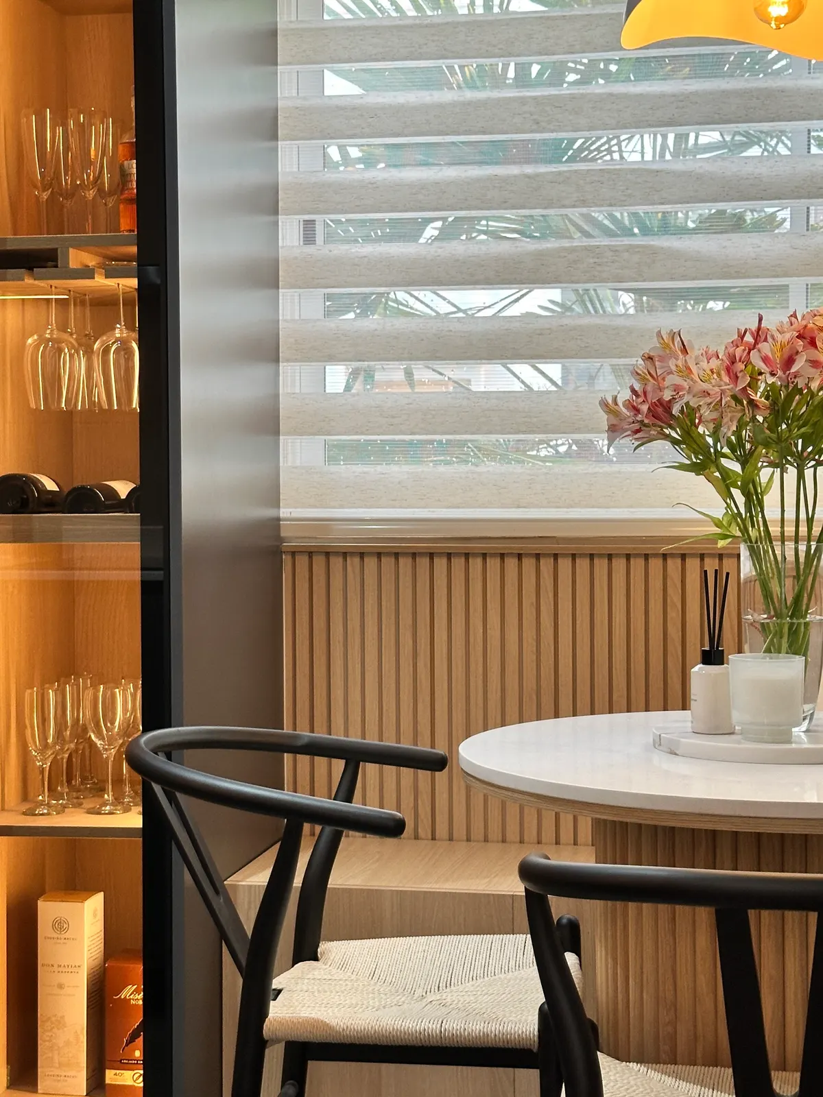 Vitrina de cristalería iluminada junto al ventanal del comedor
