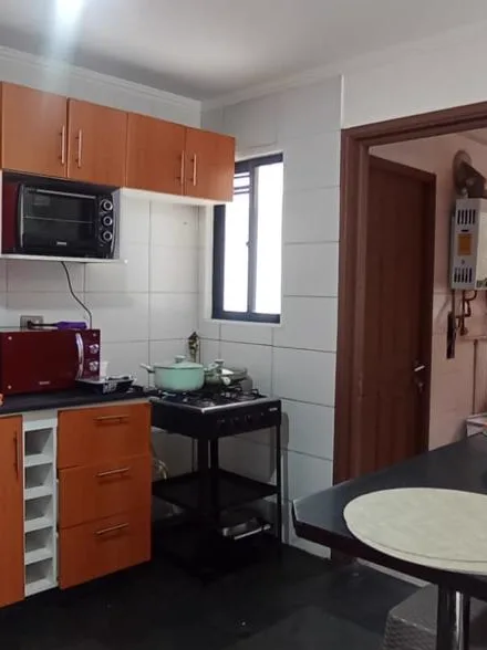 El mismo rincón antes de la reforma: la cocinilla a gas suelta sobre un carro metálico, muebles de melamina color cerezo y azulejo blanco