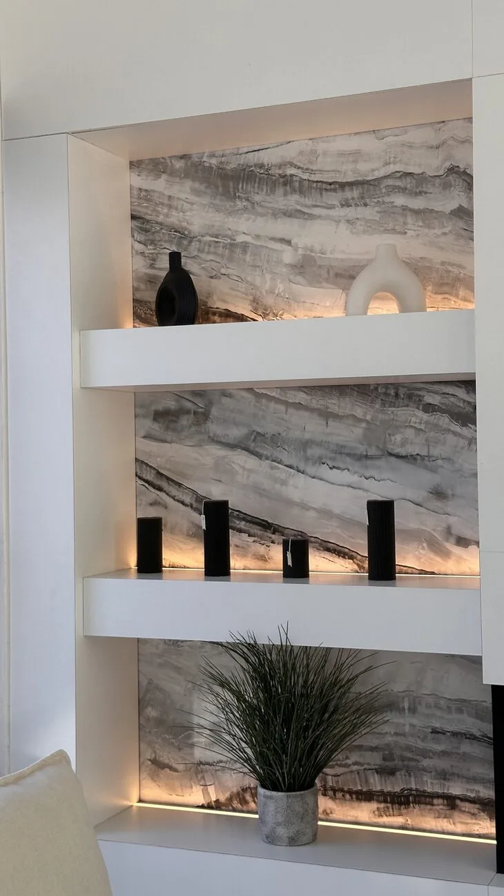 Detalle de los nichos con fondo de porcelanato veteado y repisas blancas con luz lineal