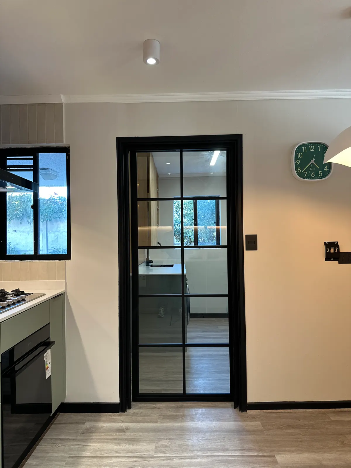 Acceso con puerta de perfilería metálica negra entre la cocina y el estar