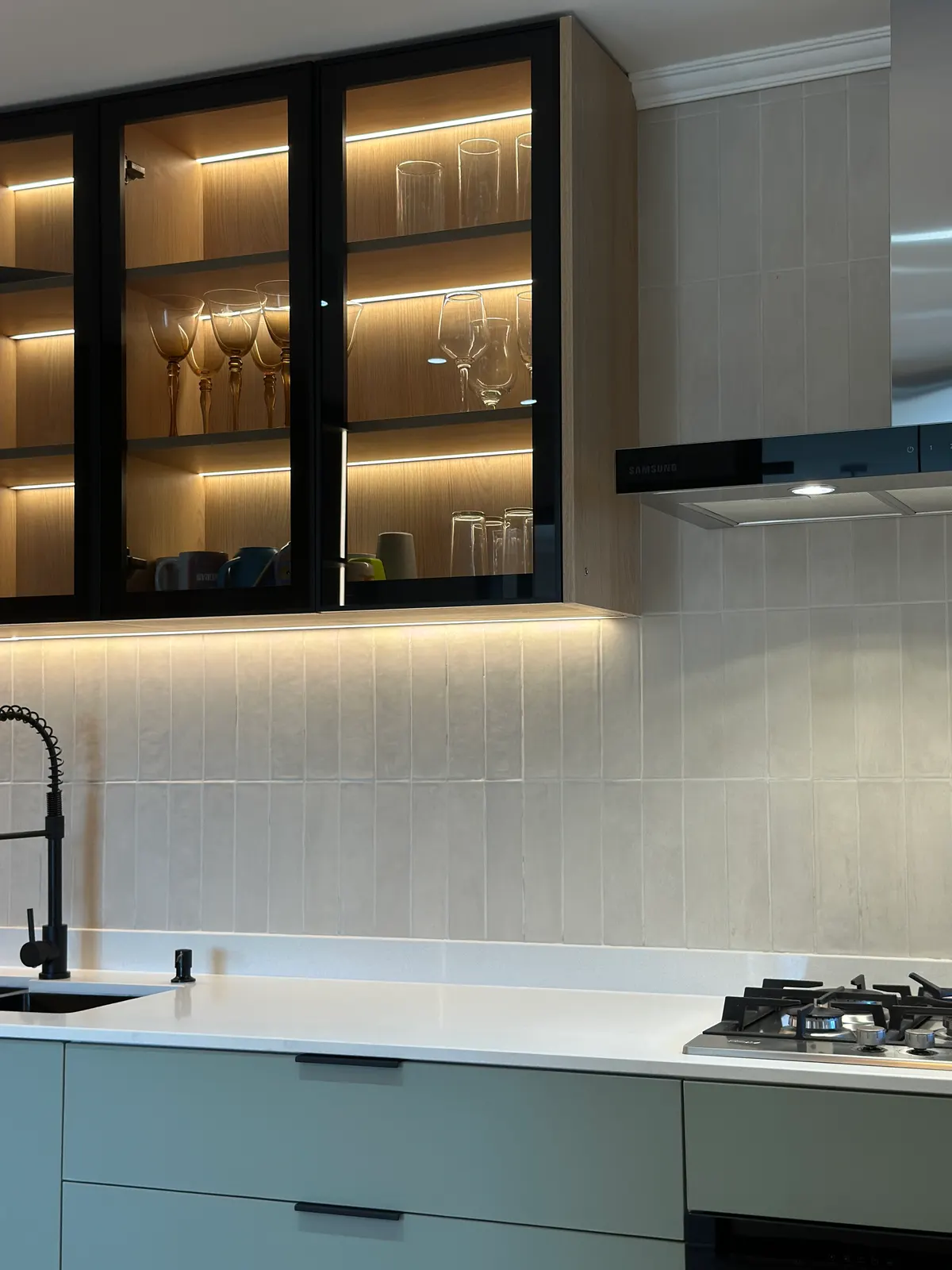 Vitrina de perfilería negra con cristalería iluminada, junto a la campana